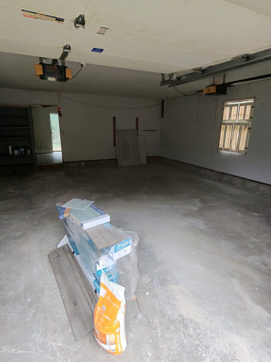 The same garage swept clear, with only a small stack of new flooring left in the middle of the empty floor.