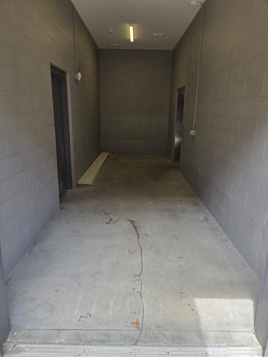 The same corridor emptied down to bare concrete, clear from end to end.